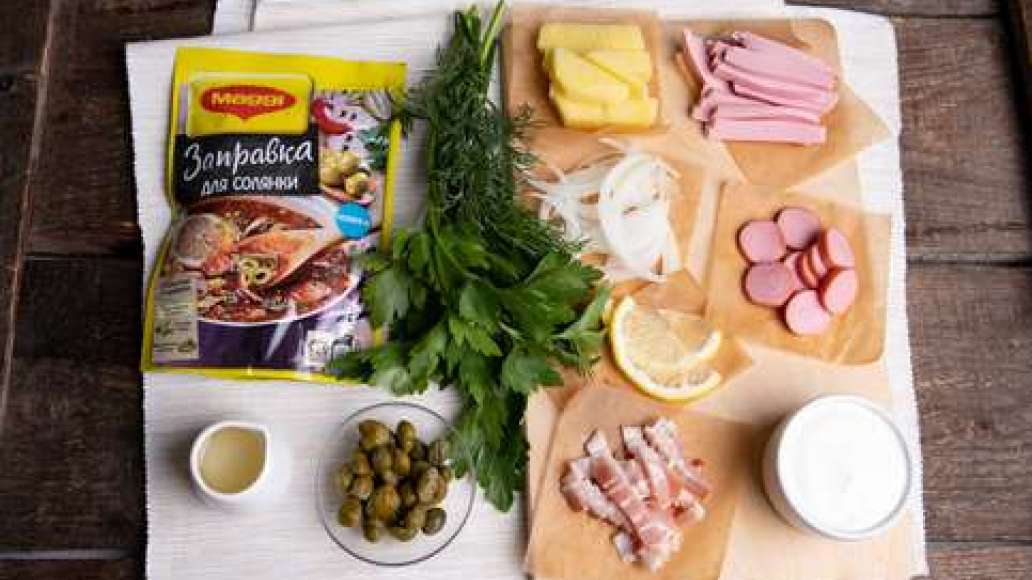 Нарезать лук полукольцами. Картофель нарезать небольшими брусочками. Нарезать бекон и докторскую колбасу тонкой соломкой, сосиски нарезать колечками. Зелень измельчить.