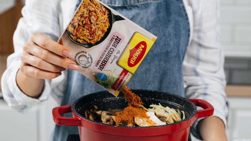 Добавить грибы. Влить воду, добавить сметану и MAGGI® НА ВТОРОЕ Смесь сухая для приготовления солянки с капустой и сосисками.