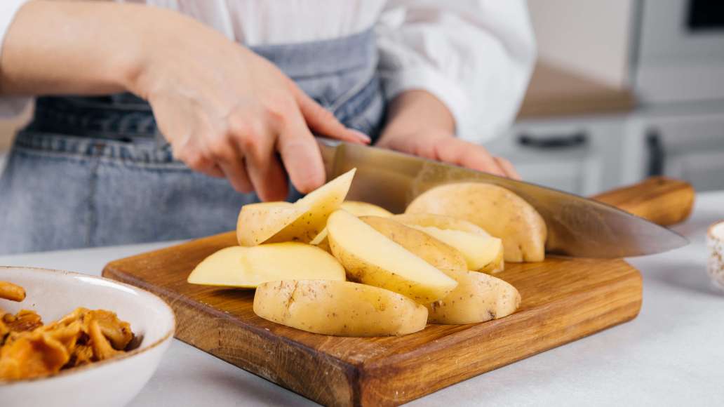 Картофель очистить и нарезать каждый клубень на 4-6 частей. Духовку разогреть до 200 °C.