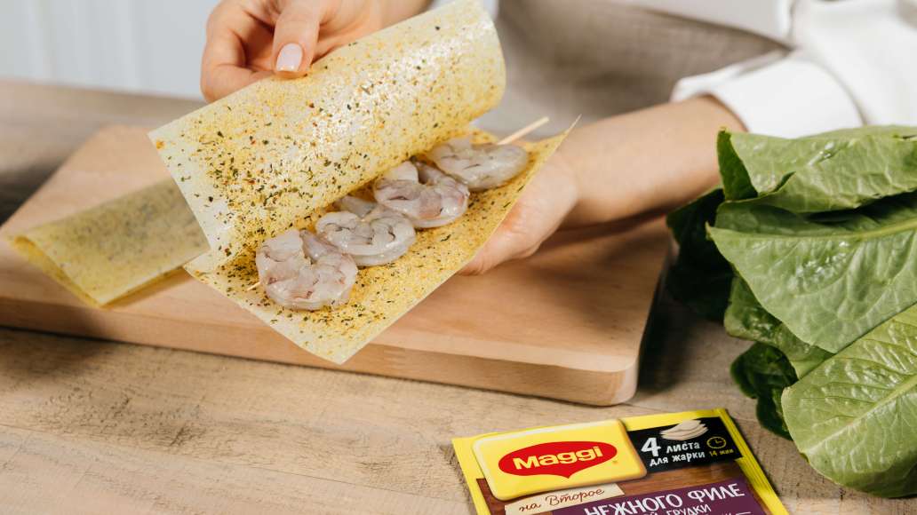 Выложить креветки на шпажках на одну половину листов для жарки MAGGI® НА ВТОРОЕ для нежного филе куриной грудки с чесноком и травами, накрыть второй половиной и слегка прижать завёрнутые креветки рукой. Выложить креветки на шпажках на одну половину листов для жарки MAGGI® НА ВТОРОЕ для нежного филе куриной грудки с чесноком и травами, накрыть второй половиной и слегка прижать завёрнутые креветки рукой.