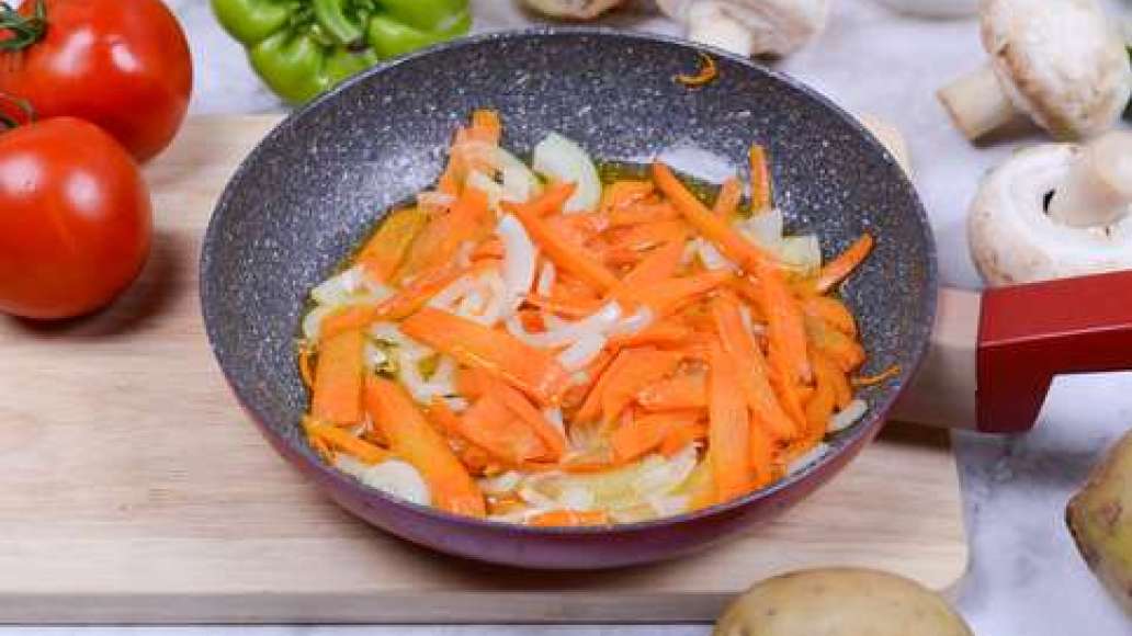Нарежьте морковь крупной соломкой, а лук - кубиками. Разогрейте сковороду, налейте масло и пассеруйте овощи 2-3 минуты.
