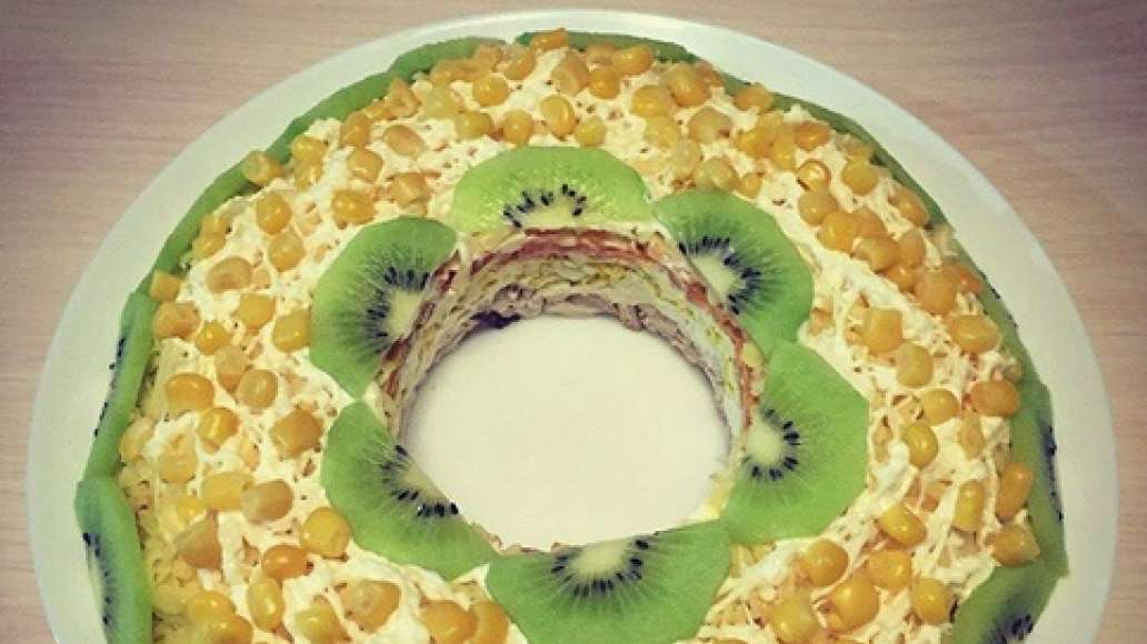 Сверху украсьте салат тонкими пластинами киви и кукурузой, как на фото. Получится очень нарядно на Новый год!