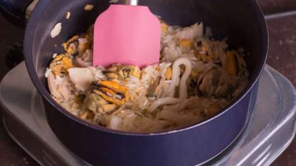 Разогреть в глубокой сковородке сливочное масло и обжарить морепродукты. Добавить рис и продолжать обжаривать, постоянно перемешивая. Влить вино и готовить, пока жидкость не испарится. Готовить еще 15-20 минут, подливая небольшими порциями воду, а затем с
