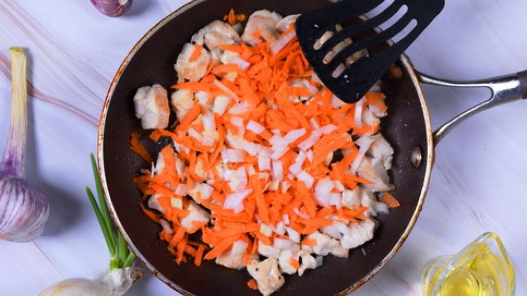 Добавьте морковь и лук в сковороду к мясу и обжаривайте 3–5 минут, постоянно помешивая. 