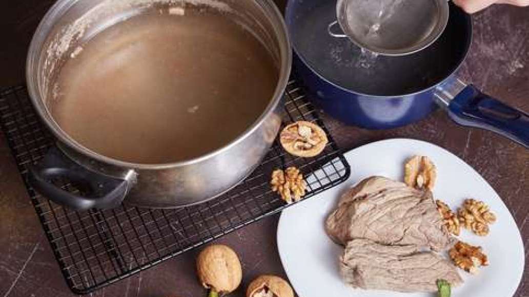 Вынуть мясо и остудить. Бульон процедить через частое сито. Измельчить орехи.