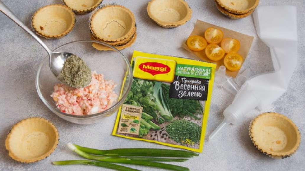Помидоры нарезать кубиками. Половину общего количества крабовых палочек нарезать кубиками. Зеленый лук мелко нарезать. Помидоры черри разрезать на половинки. 
Оставшуюся половину крабовых палочек соединить с MAGGI® Приправа Весенняя зелень и крем чиз и и