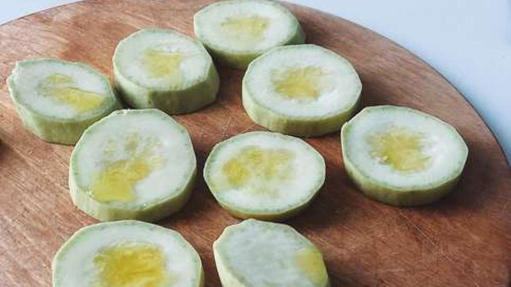 Сбрызнуть каждый кусочек кабачка оливковым маслом с одной стороны. 