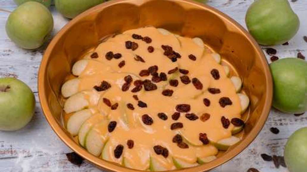 Яблоки порезать дольками, выложить в форму, залить большей частью теста. Всыпать изюм (по вкусу, но не слишком много), залить оставшимся тестом.