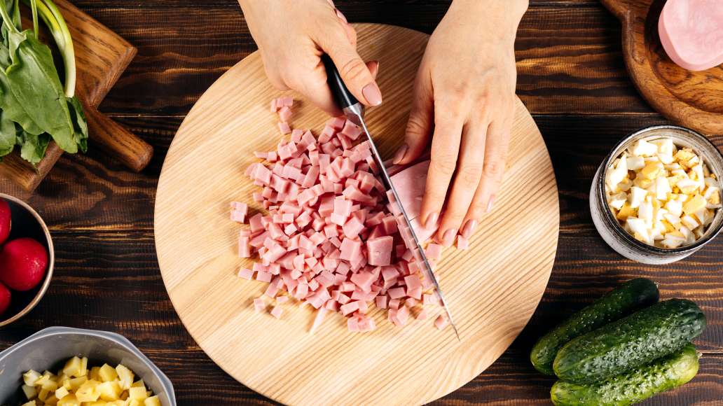 Отдельно отварить яйца вкрутую, почистить и нарезать небольшими кубиками. Аналогичным образом нарезать ветчину.