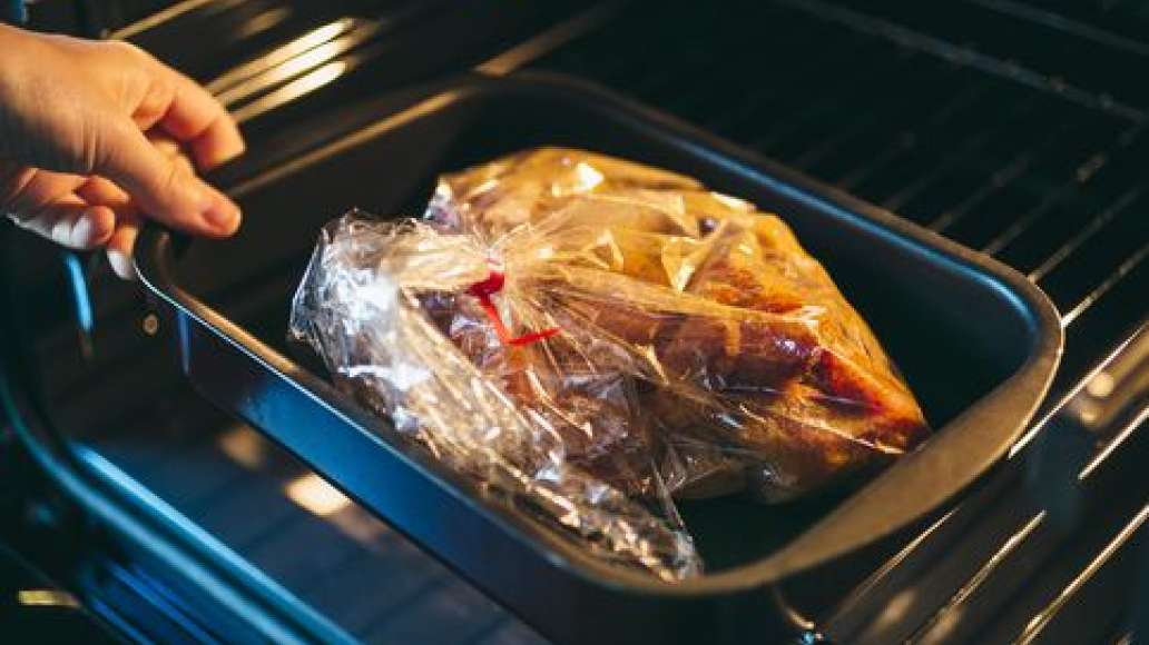 Скрепить пакет зажимом на расстоянии 6-8 см от края и аккуратно распределить смесь внутри.
Поместить пакет в форму для запекания так, чтобы хвостик от пакета был снаружи. Запекать на нижнем уровне предварительно разогретой до 200°С духовки в режиме «верх