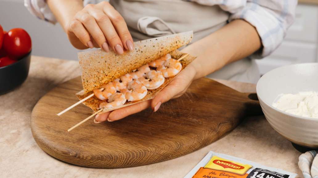 Выложить шпажки с креветками на развернутые листы MAGGI® НА ВТОРОЕ для нежного филе куриной грудки по-итальянски. Накрыть второй половиной листов и слегка прижать рукой. Выложить шпажки с креветками на развернутые листы MAGGI® НА ВТОРОЕ для нежного филе куриной грудки по-итальянски. Накрыть второй половиной листов и слегка прижать рукой.