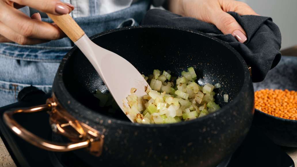 Лук и сельдерей нарезать мелкими кубиками. Разогреть растительное масло в толстодонной кастрюле или глубоком сотейнике и обжарить овощи до мягкости.