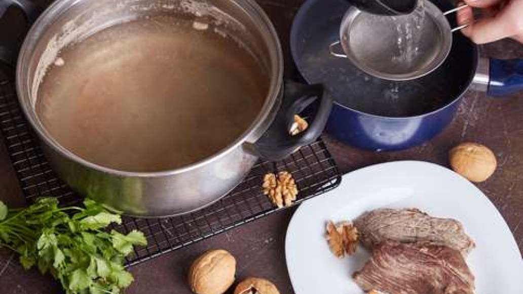 Вынуть мясо и остудить. Бульон процедить через частое сито. Измельчить орехи.