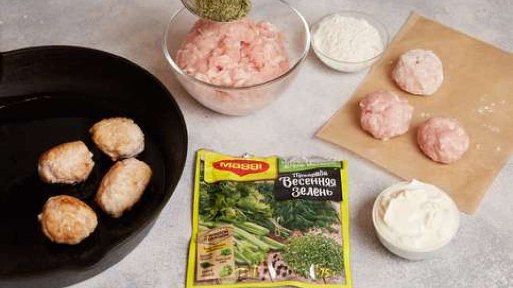 Соединить  фарш с MAGGI® Приправа Весенняя зелень и перемешать.  Сформировать небольшие круглые фрикадельки. Обвалять в муке, стряхнуть излишки.  Разогреть в сковороде растительное масло  и обжарить фрикадельки до золотистого цвета. Добавить сметану, накр