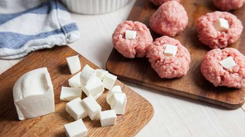 Нарезать брынзу небольшими кубиками. Каждый кубик вложить внутрь сформированных из фарша тефтелей размером с грецкий орех. 