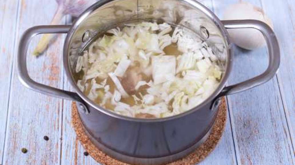 Бульон процедите и поставьте обратно на огонь. Снимите мясо с кости, нарежьте на порционные кусочки и положите в кастрюлю. Доведите до кипения и добавьте картофель. Когда суп закипит, добавьте капусту и варите 15 минут.