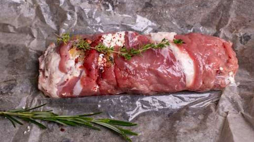 На мясо выложить ананас и сыр, посыпать сушёными помидорами. Свернуть рулетом, обвязать нитью или сколоть деревянными шпажками. На лист пергамента положить веточки тимьяна и розмарина, на них выложить мясо и плотно завернуть. Поместить в духовку и запекат