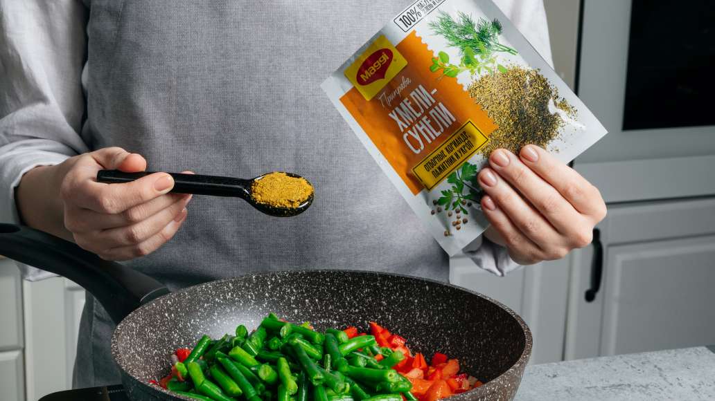 Добавить стручковую фасоль, MAGGI® хмели-сунели и тщательно перемешать.