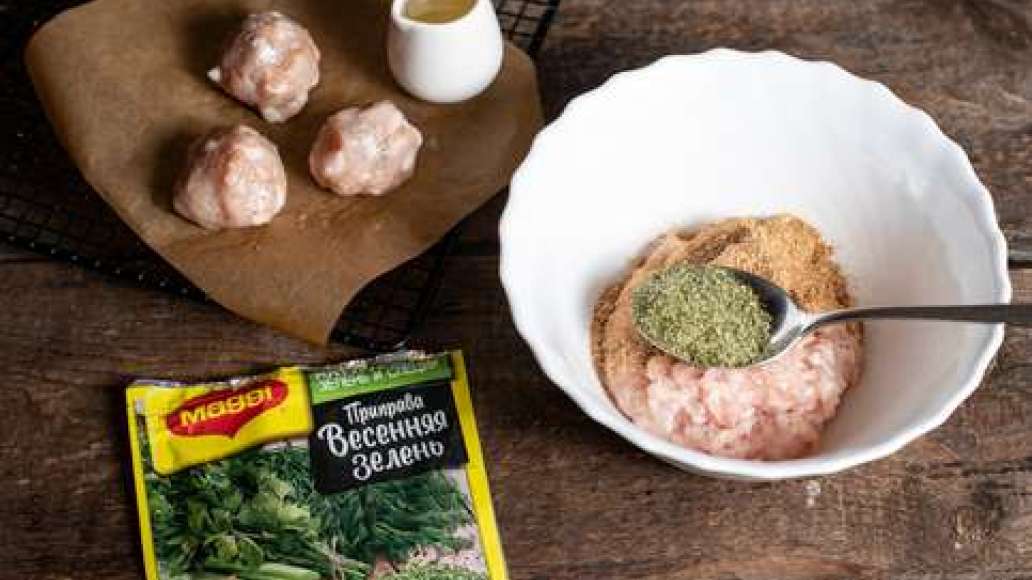 Соединить куриный  фарш с MAGGI® Приправа Весенняя зелень, добавить отруби и тщательно перемешать.  Сформировать небольшие круглые фрикадельки. Застелить противень пергаментной бумагой и смазать растительным маслом. Разложить фрикадельки и поместить проти