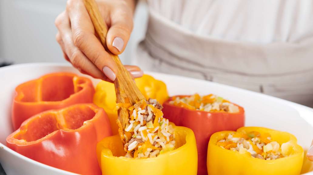 Снять массу с огня, добавить рис, посолить и поперчить по вкусу и как следует перемешать. Жаростойкую форму для запекания смазать растительным маслом. Начинить массой перцы, закрыть верхушками и выложить в форму.
