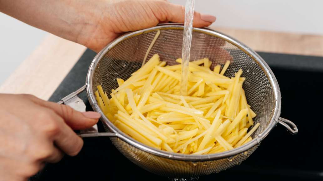 Раскалить растительное масло для фритюра. Картофель почистить и нарезать тонкой соломкой. Несколько раз промыть под струёй проточной холодной воды, чтобы удалить излишки крахмала. Раскалить растительное масло для фритюра. Картофель почистить и нарезать тонкой соломкой. Несколько раз промыть под струёй проточной холодной воды, чтобы удалить излишки крахмала.