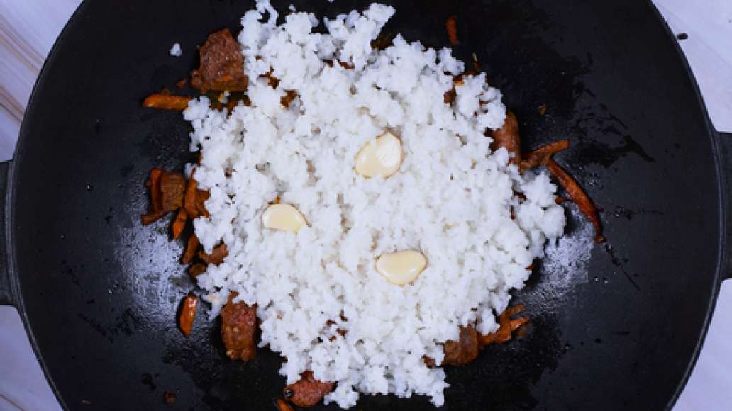 Слейте воду с риса и выложите его на мясо. Добавьте чеснок по вкусу - целиком или очищенные зубчики. Налейте воду так, чтобы она покрывала рис на 1-1,5 см. Готовьте на среднем огне под закрытой крышкой 20 минут. Затем убавьте огонь до минимума и готовьте 