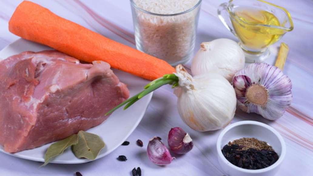 Подготовьте ингредиенты, промойте мясо и нарежьте порционным кусочками. Сварите рис до полуготовности.