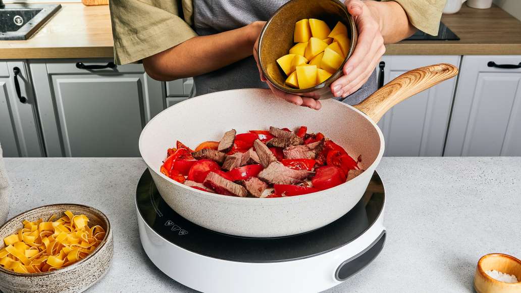 Пока мясо тушится, очистите картофель и нарежьте на небольшие кусочки,
затем добавьте в сковороду и готовьте ещё 25-30 минут.