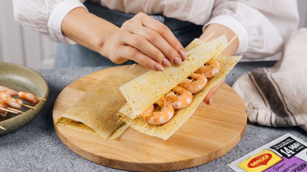 Выложить шпажки с креветками на развернутые листы MAGGI® НА ВТОРОЕ для нежного филе куриной грудки с чесноком и травами. Накрыть второй половиной листов и прижать рукой. Выложить шпажки с креветками на развернутые листы MAGGI® НА ВТОРОЕ для нежного филе куриной грудки с чесноком и травами. Накрыть второй половиной листов и прижать рукой.