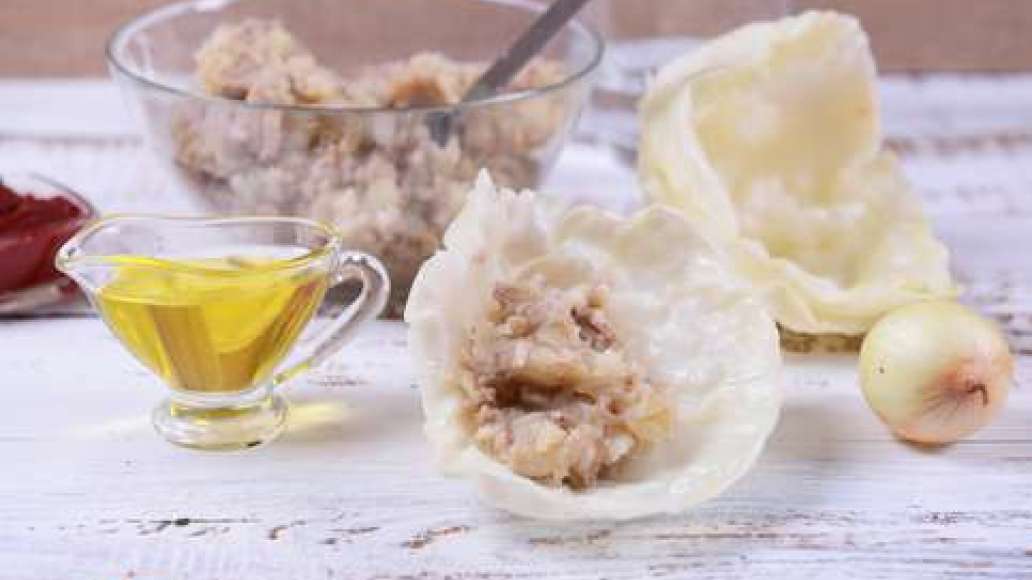Когда картофель приготовится, слейте воду и растолките в пюре. Добавьте к фаршу, перемешайте. В большой кастрюле вскипятите воду, посолите и опустите в неё кочан капусты. Варите 3-5 минут, затем выньте кочан и остудите. Снимите листья, которые стали мягки