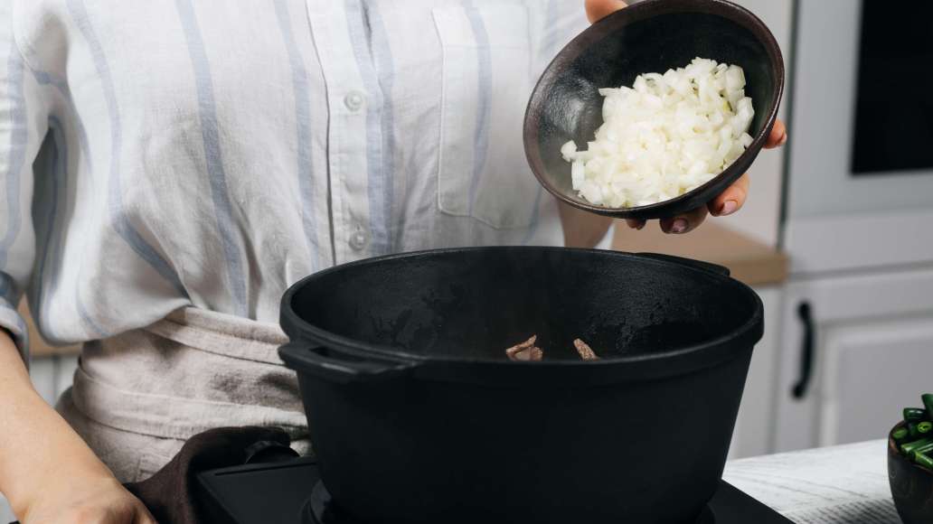 Обжарить на разогретом растительном масле мясо со всех сторон до лёгкой корочки на сильном огне. Убавить огонь до слабого, добавить лук и тушить, периодически помешивая, 10 минут.