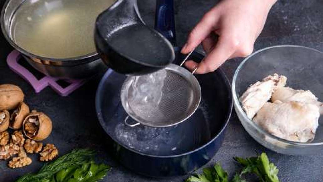 Сварить куриный бульон, процедить через частое сито. Вынуть мясо, остудить и отделить от костей. Слить жидкость из кастрюли с нутом.