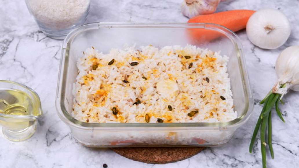 В форму для запекания выложите курицу с овощами, сверху выложите слой риса,посыпьте специями. Влейте питьевую воду или бульон так, чтобы он покрывал рис. Поместите в рис целый очищенный зубчик чеснока. 