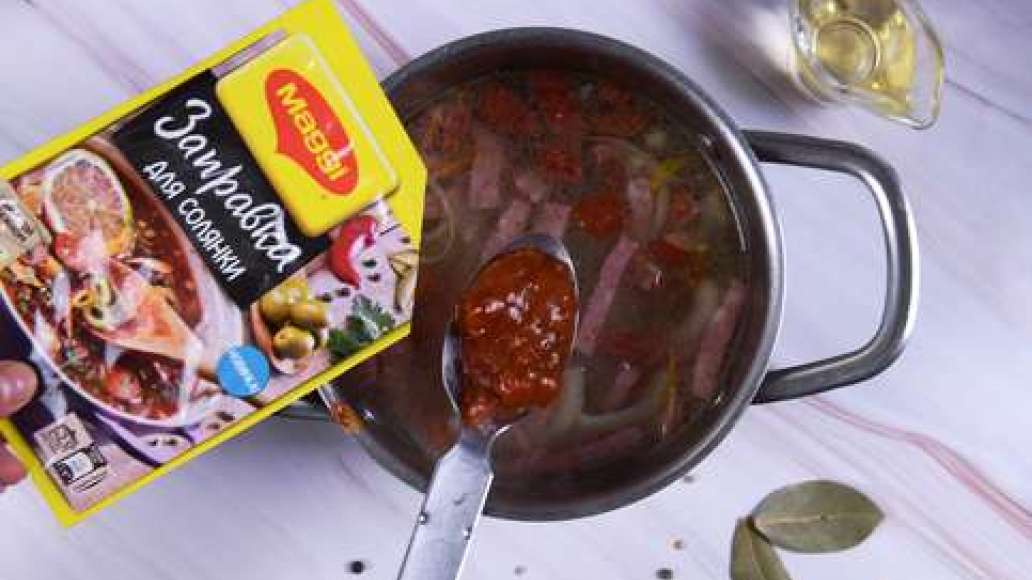 Добавьте в кастрюлю обжаренную колбасу, MAGGI® Заправка для солянки и 2 столовые ложки рассола.