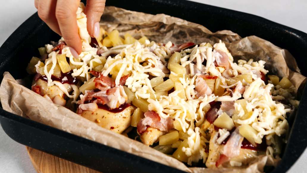 Выложить поверх филе кусочки ананаса, посыпать сыром и беконом.
