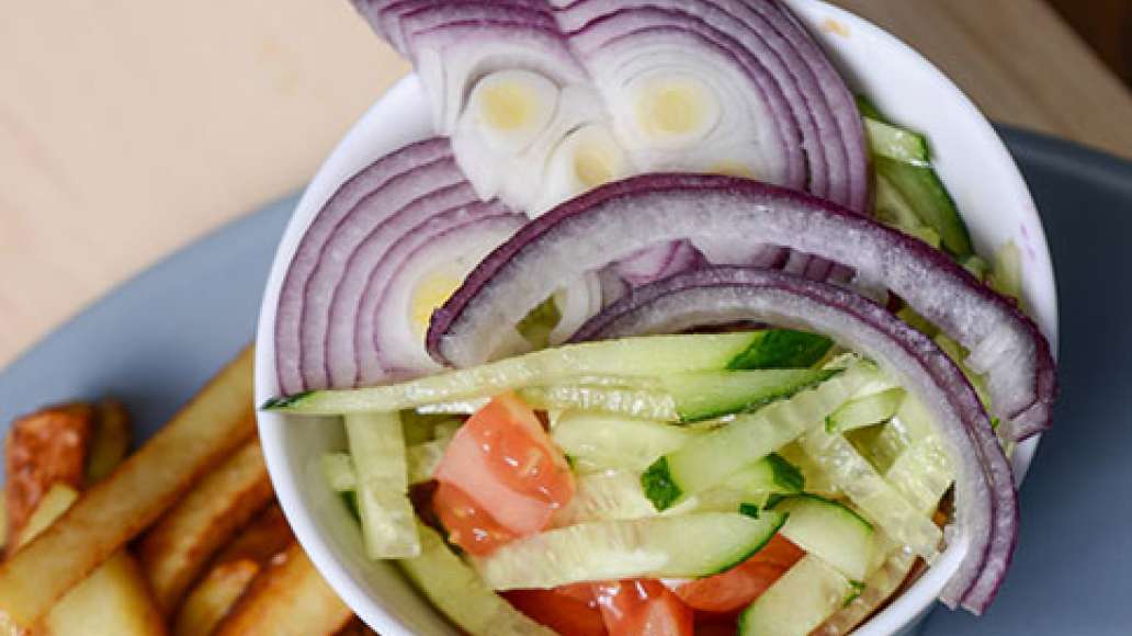 Нашинкуйте капусту, добавьте соль по вкусу и помните руками. Нарежьте лук полукольцами. Нарежьте помидоры небольшими кубиками, огурец нарежьте соломкой. Почистите картофель и нарежьте соломкой. Обжарьте в масле до готовности.