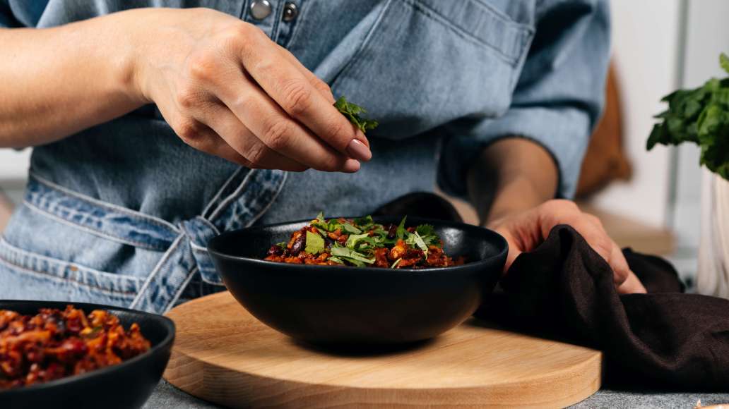 Снять с огня, попробовать на вкус и при необходимости досолить. Кинзу мелко порезать (часть оставить для подачи) и вмешать в лобио. Разложить блюдо по тарелкам и украсить оставшейся кинзой.