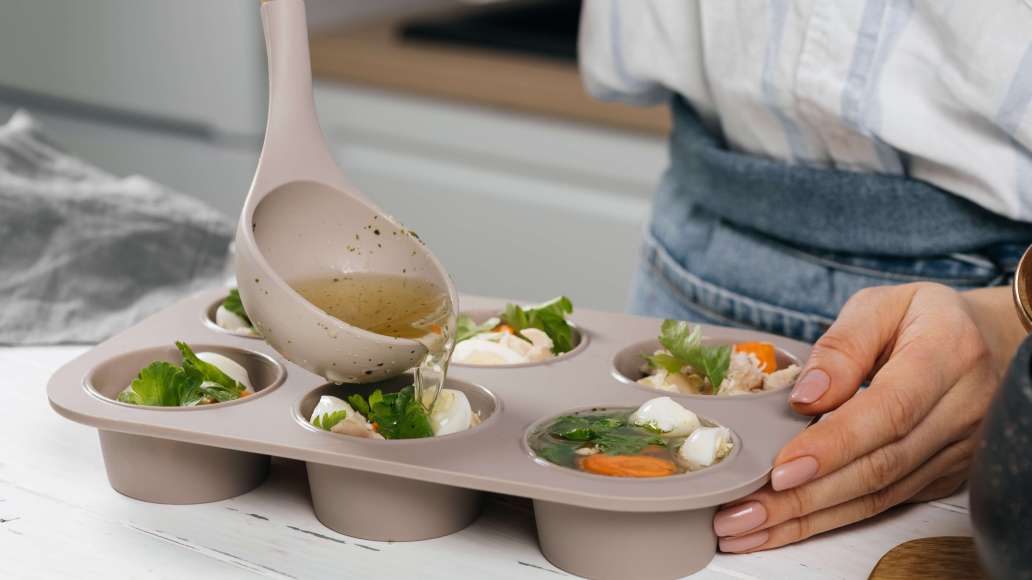 Разложить мясо с морковью и яйцами по порционным формам или лоткам (для большей яркости блюда добавить также листики свежей петрушки). Аккуратно залить сверху бульон и отправить холодец до полного застывания в холодильник (6–8 часов).