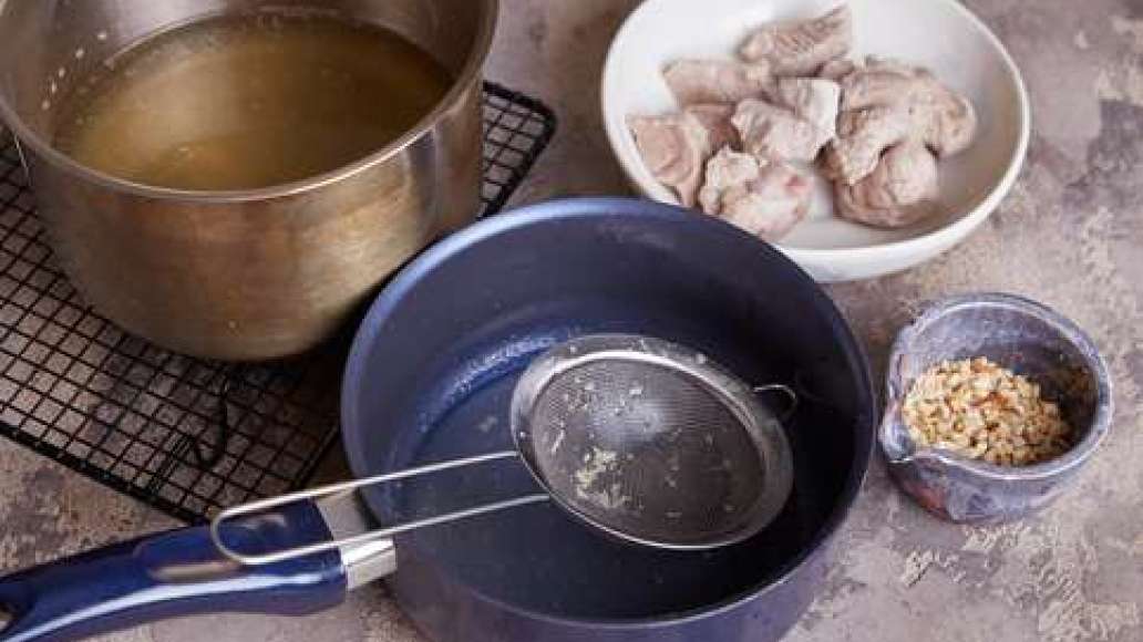 Залить мясо водой и сварить бульон.  Вынуть и остудить мясо, нарезать небольшими кусочками. Бульон процедить через частое сито.  Очистить грецкие орехи.