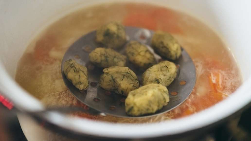 При помощи двух чайных ложек сформировать из теста клецки. Опустить клецки в горячий бульон (ложкой можно помочь им отлепиться от дна) и немного проварить (постоянно мешать не нужно, чтобы не разрушить нежные клецки).
Шаг 7 - Куриный суп с заварными клецками