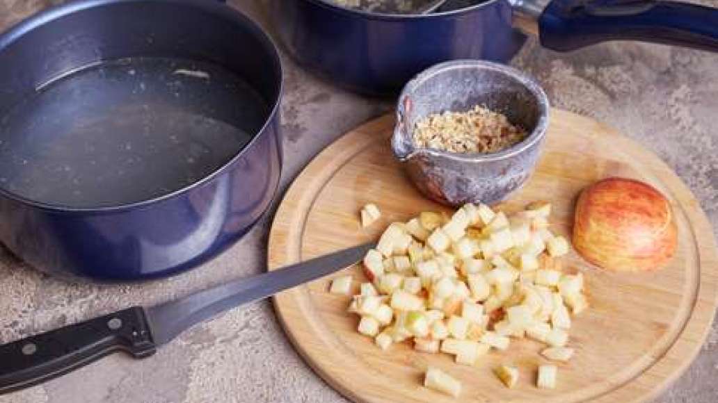 Залить мясо водой и сварить бульон.  Вынуть и остудить мясо, нарезать небольшими кусочками. Бульон процедить через частое сито.  Измельчить  грецкие орехи.  Яблоко очистить, удалить семена, нарезать мелкими кубиками. Белую часть лука порея нарезать.