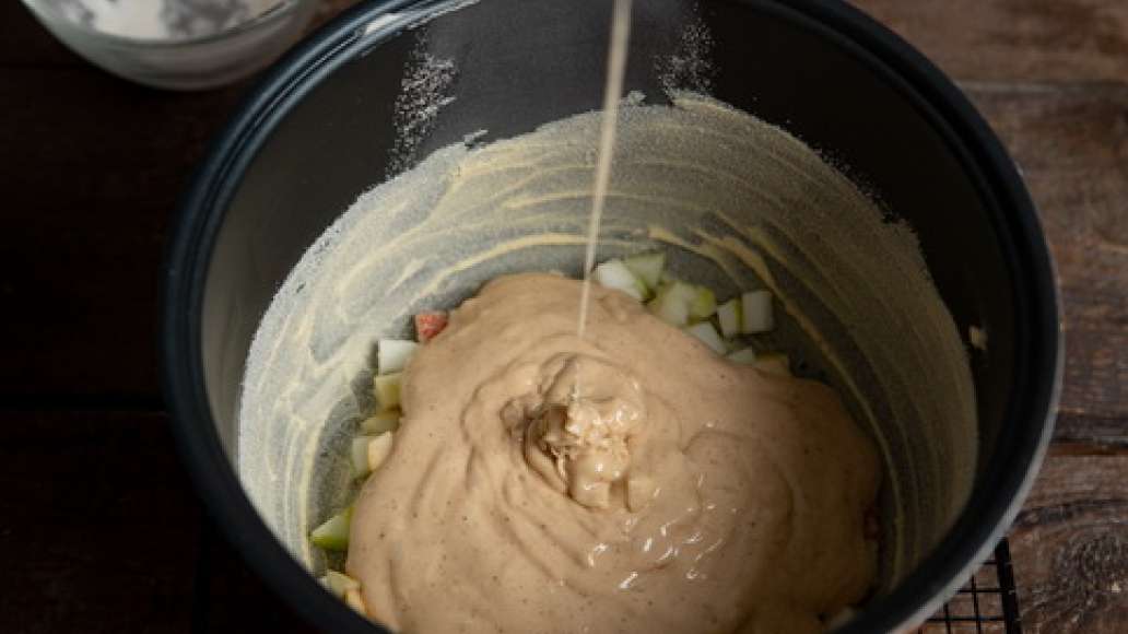 Кастрюлю мультиварки смазать сливочным маслом,  посыпать манкой и стряхнуть излишки. Порезать яблоки и выложить в кастрюлю. Вылить в нее тесто, закрыть крышкой и готовить в режиме «Выпечка»  в течение 40 минут. 