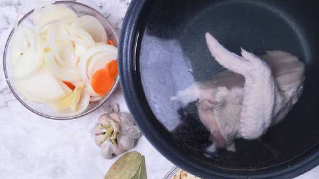 Поместите курицу в чашу мультиварки, налейте воду. Нарежьте лук полукольцами, морковь - кружочками, измельчите чеснок. Добавьте всё в чашу к курице.