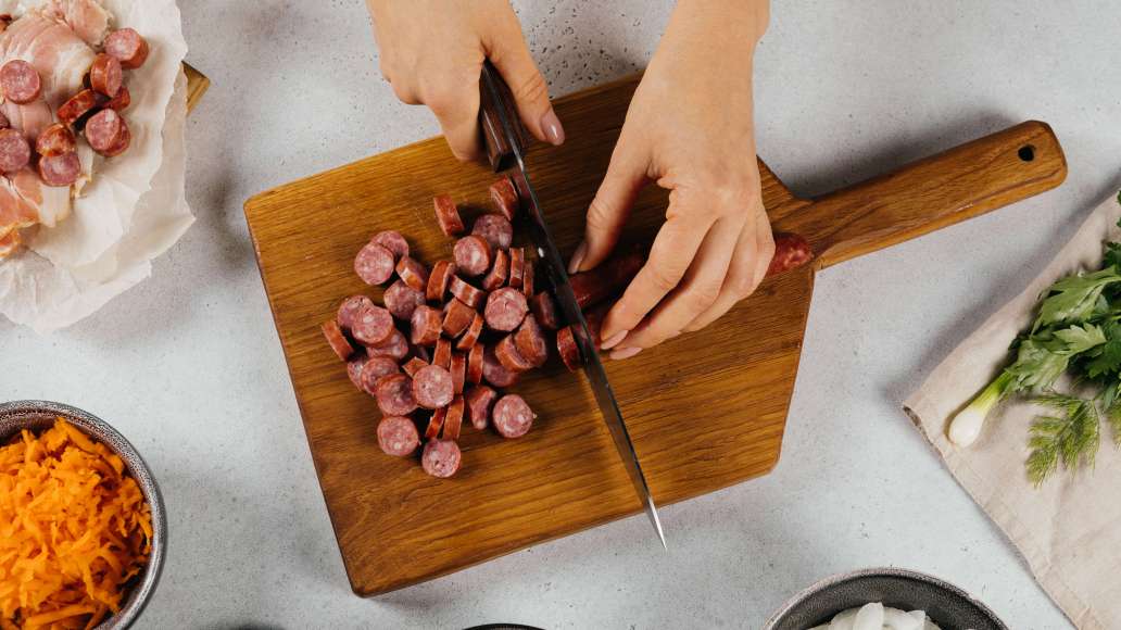 Нарезать колбаски кружочками, бекон тонкими полосками.