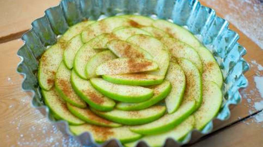 Яблоки порежьте на кусочки, выложите в форму. Посыпьте яблоки корицей. Залейте тестом, аккуратно распределив его по поверхности фруктов.
