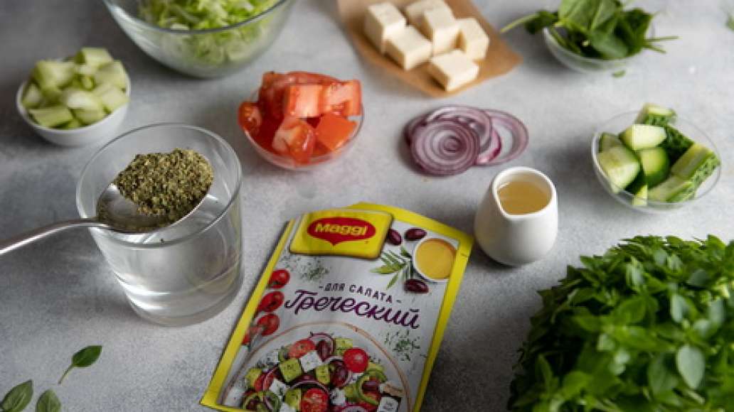 Салат айсберг нарезать соломкой. Брынзу нарезать кубиками. Стебли сельдерея, помидоры и огурцы нарезать кубиками. Красный лук нарезать кольцами. В небольшой емкости соединить 3 ст. л. горячей воды и MAGGI® Приправа Весенняя зелень, оставить на 3 – 5 минут