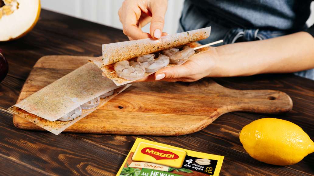 Выложить креветки на шпажках на одну половину листов для жарки MAGGI® НА ВТОРОЕ для нежного филе индейки с прованскими травами, накрыть второй половиной и слегка прижать завёрнутые креветки рукой. Выложить креветки на шпажках на одну половину листов для жарки MAGGI® НА ВТОРОЕ для нежного филе индейки с прованскими травами, накрыть второй половиной и слегка прижать завёрнутые креветки рукой.
