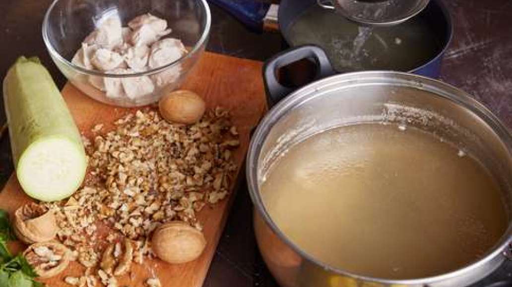 Залить индейку водой и сварить бульон. Вынуть мясо, бульон процедить через частое сито. Измельчить орехи.